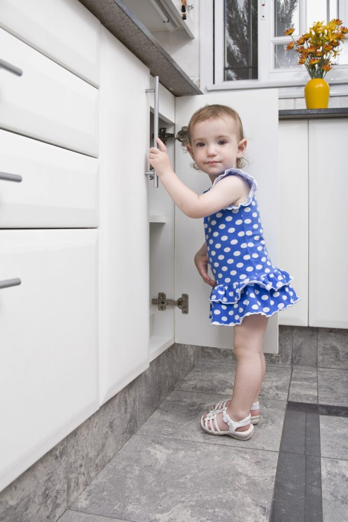 girl opening cupboard in kitchen